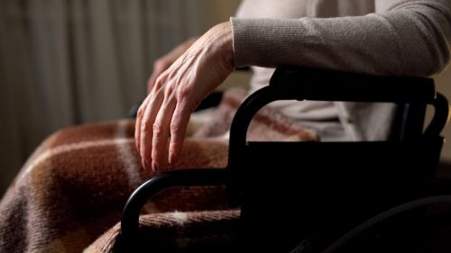 Close up shot of the hand of an elderly person sitting in a wheel chair - types of nursing home abuse concept